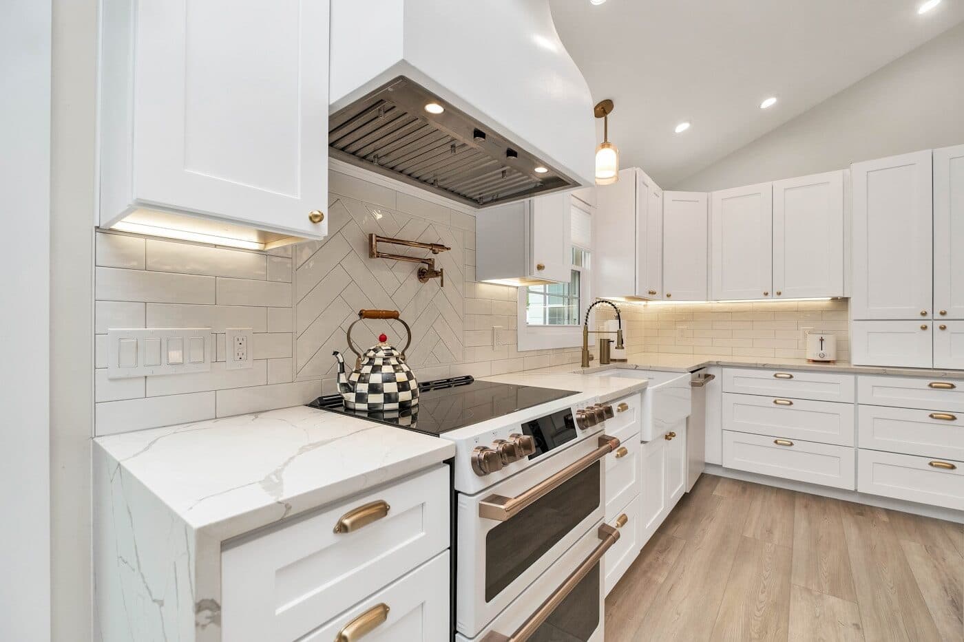 A white shaker kitchen with brass handles, a quartz worktop and a metro-tiled splashback