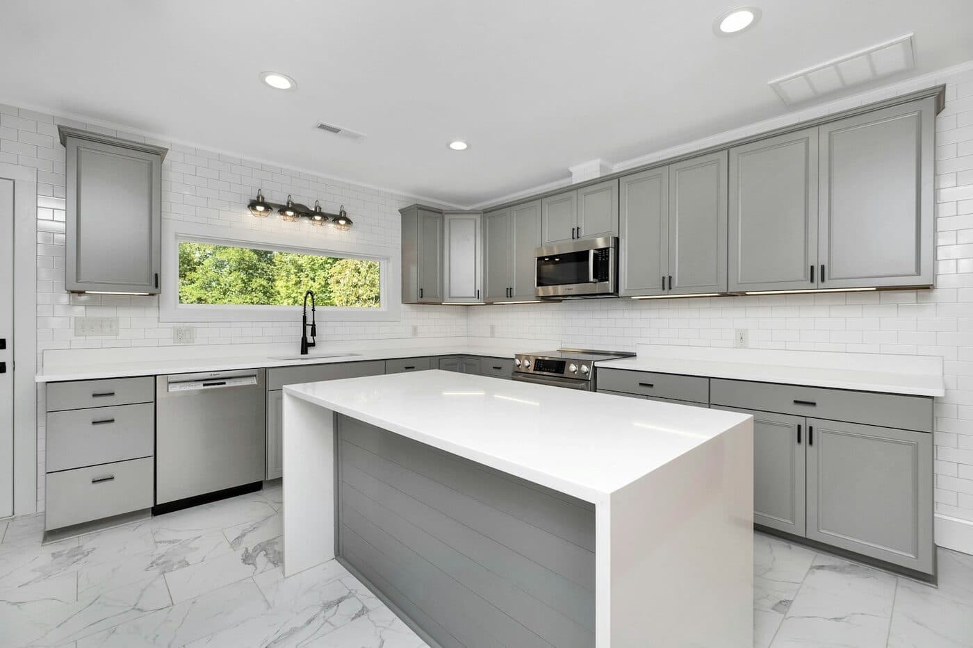 A traditional painted kitchen in grey with framed cabinet doors and glazed wall units