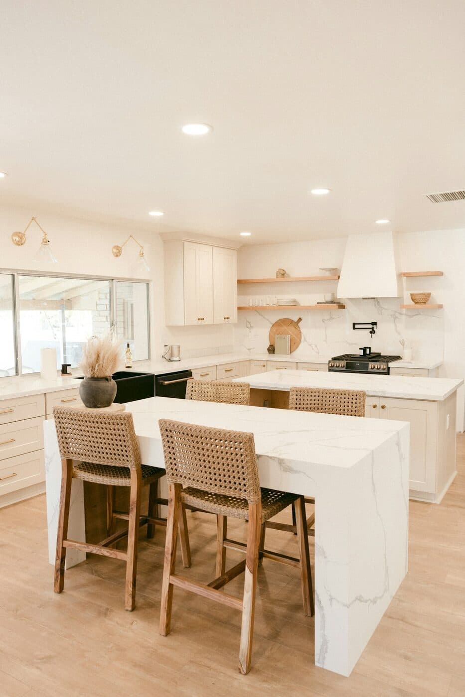 A minimal kitchen with flat-fronted white doors, a marble worktop and open shelving